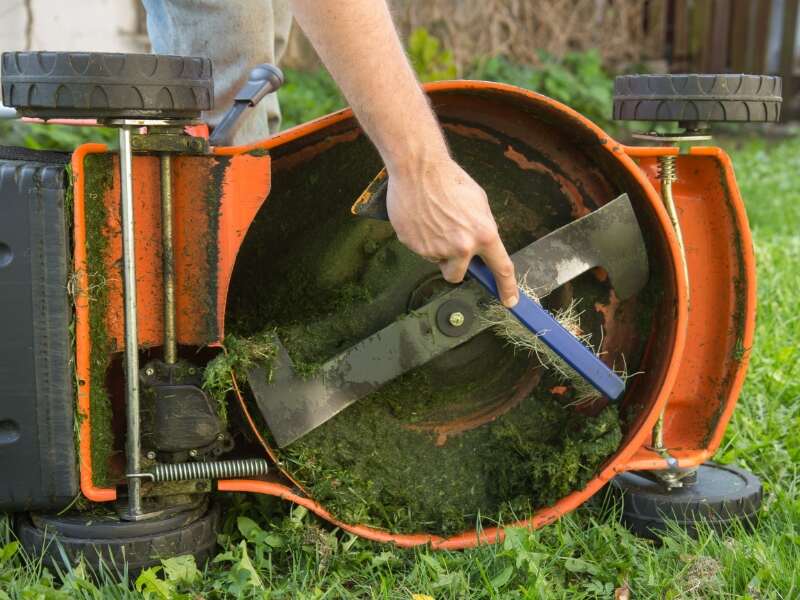 man cleaning a lawn mower