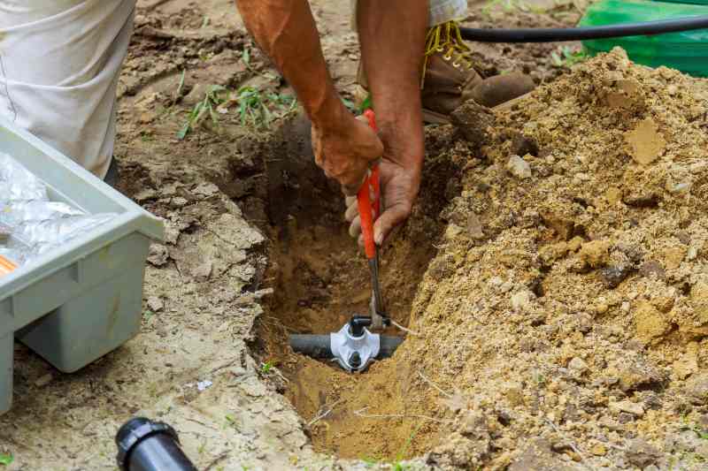 man working on Underground Sprinkler System to Water the Yard 